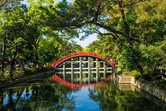 A red bridge over water in a Japanese-style garden