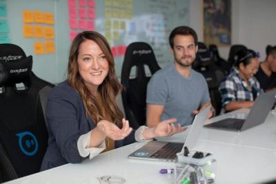 people in a business meeting; a woman is speaking and a man is looking at her admiringly