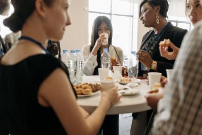 A group of coworkers standing around a tall table eating pastries