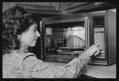 A woman presses buttons on a microwave